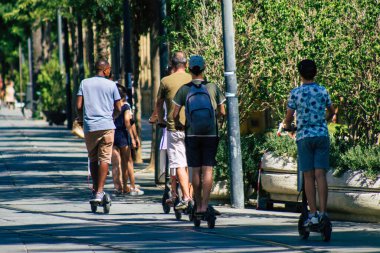 Seville İspanya 11 Ağustos 2021 Seville sokaklarında elektrikli scooterla dolaşan insanlar, küçük bir iç yanmalı motorlar ve merkezde bir güverte ile çalışıyorlar.
