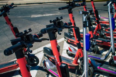 Seville İspanya 21 Ağustos 2021 Sevilla caddelerinde park etmiş küçük bir iç yanmalı motorlar ve merkezde bir güverte ile çalışan elektrikli scooter.