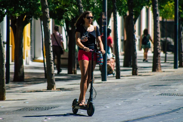 Seville İspanya 4 Eylül 2021 Seville sokaklarında elektrikli scooterla dolaşan insanlar, küçük bir iç yanmalı motorlar ve merkezde bir güverte ile çalışıyorlar.