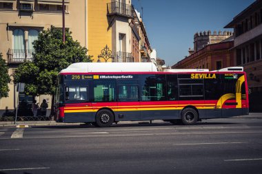 Seville, İspanya, 4 Ekim 2025 otobüsü Sevilla 'nın tarihi şehir merkezinden geçerek dar, pitoresk caddelerden geçer..