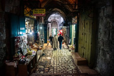 Kudüs, İsrail, 13 Aralık 2025 Kudüs 'ün Hristiyan Mahallesi' ndeki dar sokaklar ve atmosferik ışık oyunları yerel satıcılar tarafından sergilenen çeşitli ürünlere bir göz atma olanağı sağlıyor..