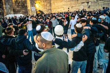 Kudüs, İsrail, 14 Aralık 2025 Yahudi gençler Eski Kudüs 'teki Hanuka kutlamaları sırasında Batı Duvarı (Kotel) önünde sevinçle omuz omuza ve dans ediyorlar..