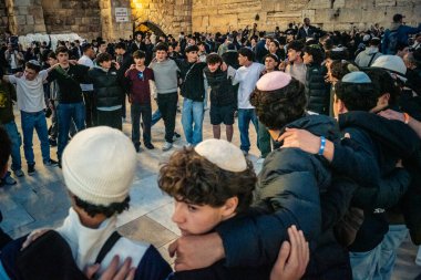 Kudüs, İsrail, 14 Aralık 2025 Yahudi gençler Eski Kudüs 'teki Hanuka kutlamaları sırasında Batı Duvarı (Kotel) önünde sevinçle omuz omuza ve dans ediyorlar..