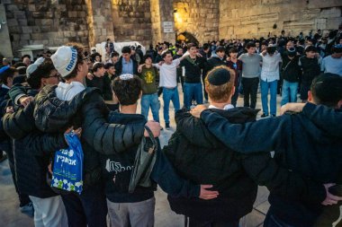 Kudüs, İsrail, 14 Aralık 2025 Yahudi gençler Eski Kudüs 'teki Hanuka kutlamaları sırasında Batı Duvarı (Kotel) önünde sevinçle omuz omuza ve dans ediyorlar..