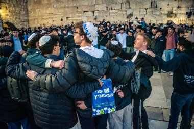 Kudüs, İsrail, 14 Aralık 2025 Yahudi gençler Eski Kudüs 'teki Hanuka kutlamaları sırasında Batı Duvarı (Kotel) önünde sevinçle omuz omuza ve dans ediyorlar..