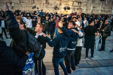 Kudüs, İsrail, 14 Aralık 2025 Yahudi gençler Eski Kudüs 'teki Hanuka kutlamaları sırasında Batı Duvarı (Kotel) önünde sevinçle omuz omuza ve dans ediyorlar..