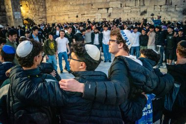 Kudüs, İsrail, 14 Aralık 2025 Yahudi gençler Eski Kudüs 'teki Hanuka kutlamaları sırasında Batı Duvarı (Kotel) önünde sevinçle omuz omuza ve dans ediyorlar..