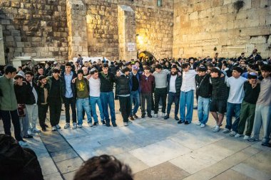 Kudüs, İsrail, 14 Aralık 2025 Yahudi gençler Eski Kudüs 'teki Hanuka kutlamaları sırasında Batı Duvarı (Kotel) önünde sevinçle omuz omuza ve dans ediyorlar..