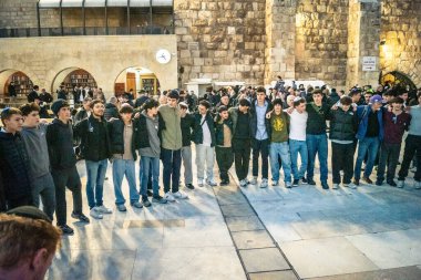 Kudüs, İsrail, 14 Aralık 2025 Yahudi gençler Eski Kudüs 'teki Hanuka kutlamaları sırasında Batı Duvarı (Kotel) önünde sevinçle omuz omuza ve dans ediyorlar..