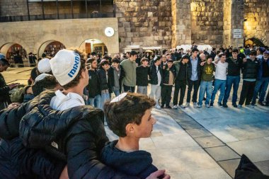 Kudüs, İsrail, 14 Aralık 2025 Yahudi gençler Eski Kudüs 'teki Hanuka kutlamaları sırasında Batı Duvarı (Kotel) önünde sevinçle omuz omuza ve dans ediyorlar..