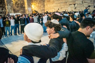 Kudüs, İsrail, 14 Aralık 2025 Yahudi gençler Eski Kudüs 'teki Hanuka kutlamaları sırasında Batı Duvarı (Kotel) önünde sevinçle omuz omuza ve dans ediyorlar..