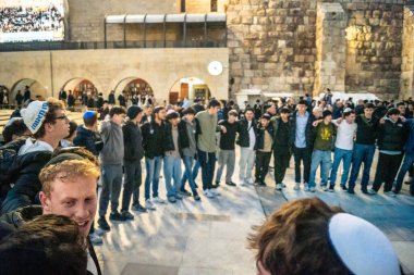 Kudüs, İsrail, 14 Aralık 2025 Yahudi gençler Eski Kudüs 'teki Hanuka kutlamaları sırasında Batı Duvarı (Kotel) önünde sevinçle omuz omuza ve dans ediyorlar..