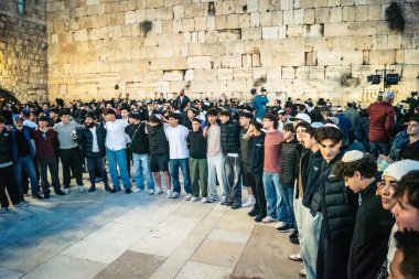 Kudüs, İsrail, 14 Aralık 2025 Yahudi gençler Eski Kudüs 'teki Hanuka kutlamaları sırasında Batı Duvarı (Kotel) önünde sevinçle omuz omuza ve dans ediyorlar..