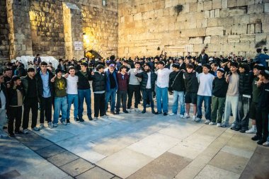 Kudüs, İsrail, 14 Aralık 2025 Yahudi gençler Eski Kudüs 'teki Hanuka kutlamaları sırasında Batı Duvarı (Kotel) önünde sevinçle omuz omuza ve dans ediyorlar..