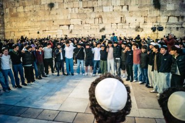 Kudüs, İsrail, 14 Aralık 2025 Yahudi gençler Eski Kudüs 'teki Hanuka kutlamaları sırasında Batı Duvarı (Kotel) önünde sevinçle omuz omuza ve dans ediyorlar..