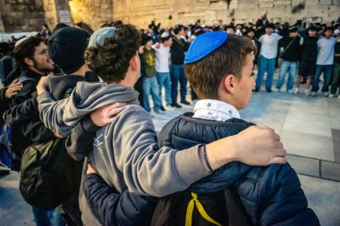 Kudüs, İsrail, 14 Aralık 2025 Yahudi gençler Eski Kudüs 'teki Hanuka kutlamaları sırasında Batı Duvarı (Kotel) önünde sevinçle omuz omuza ve dans ediyorlar..