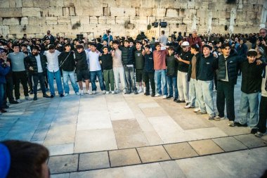 Kudüs, İsrail, 14 Aralık 2025 Yahudi gençler Eski Kudüs 'teki Hanuka kutlamaları sırasında Batı Duvarı (Kotel) önünde sevinçle omuz omuza ve dans ediyorlar..