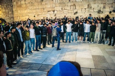 Kudüs, İsrail, 14 Aralık 2025 Yahudi gençler Eski Kudüs 'teki Hanuka kutlamaları sırasında Batı Duvarı (Kotel) önünde sevinçle omuz omuza ve dans ediyorlar..