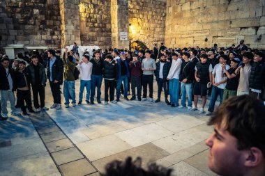 Kudüs, İsrail, 14 Aralık 2025 Yahudi gençler Eski Kudüs 'teki Hanuka kutlamaları sırasında Batı Duvarı (Kotel) önünde sevinçle omuz omuza ve dans ediyorlar..
