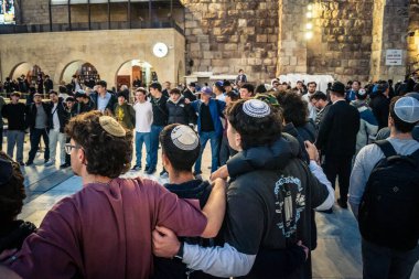Kudüs, İsrail, 14 Aralık 2025 Yahudi gençler Eski Kudüs 'teki Hanuka kutlamaları sırasında Batı Duvarı (Kotel) önünde sevinçle omuz omuza ve dans ediyorlar..
