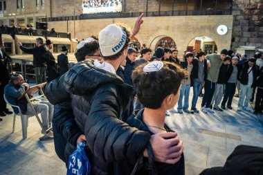Kudüs, İsrail, 14 Aralık 2025 Yahudi gençler Eski Kudüs 'teki Hanuka kutlamaları sırasında Batı Duvarı (Kotel) önünde sevinçle omuz omuza ve dans ediyorlar..