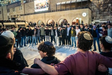 Kudüs, İsrail, 14 Aralık 2025 Yahudi gençler Eski Kudüs 'teki Hanuka kutlamaları sırasında Batı Duvarı (Kotel) önünde sevinçle omuz omuza ve dans ediyorlar..