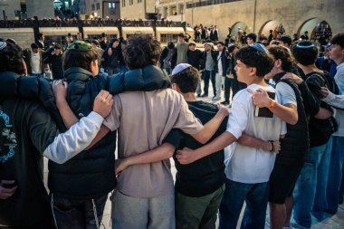 Kudüs, İsrail, 14 Aralık 2025 Yahudi gençler Eski Kudüs 'teki Hanuka kutlamaları sırasında Batı Duvarı (Kotel) önünde sevinçle omuz omuza ve dans ediyorlar..