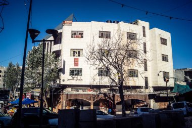 Hebron, Batı Şeria, 17 Aralık 2025 Vibrant sokak yaşamı ve Filistin 'deki El Halil' in merkezindeki işlek pazarlar. Sarı taksiler ve kalabalık kalabalık kalabalık işlek caddelerde geziniyor..