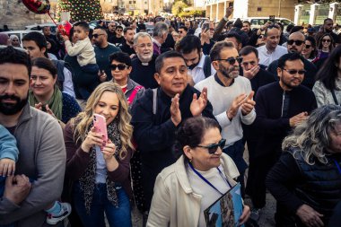 Beytüllahim, Batı Şeria, 25 Aralık 2025. İsa 'ya tapanların yakın çekimleri, İsa' nın Doğumu Kilisesi 'nin önünde rahipler tarafından verilen açık hava konserinde kendilerini adamış bir şekilde şarkı söylemeleri..