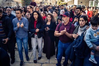 Beytüllahim, Batı Şeria, 25 Aralık 2025. İsa 'ya tapanların yakın çekimleri, İsa' nın Doğumu Kilisesi 'nin önünde rahipler tarafından verilen açık hava konserinde kendilerini adamış bir şekilde şarkı söylemeleri..