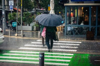 Tel Aviv, İsrail, 29 Aralık 2025. Yayalar şemsiyelerle yağmurda yürür Orta Doğu 'nun en modern şehirlerinden biri olan Tel Aviv sokaklarında..