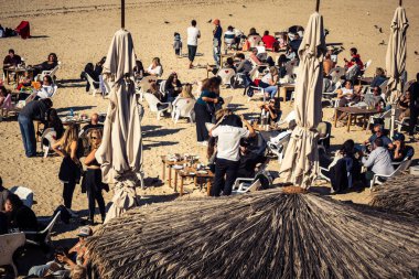Tel Aviv, İsrail, 13 Ocak 2026 Akdeniz kıyısındaki bir restoranda oturan insanlar. Kumsal, dalgalar ve deniz kenarındaki gezinti, İsrail kıyılarının doğal güzelliğinin olağanüstü bir manzarası..