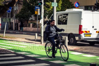 Tel Aviv, İsrail, 14 Ocak 2026. Bisikletçiler, Tel Aviv 'de Rothschild Bulvarı boyunca, modern şehir yaşam tarzını yansıtan, ağaçlarla çevrili, canlı bir merkez caddeye gidiyorlar..