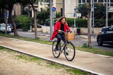 Tel Aviv, İsrail, 14 Ocak 2026. Bisikletçiler, Tel Aviv 'de Rothschild Bulvarı boyunca, modern şehir yaşam tarzını yansıtan, ağaçlarla çevrili, canlı bir merkez caddeye gidiyorlar..