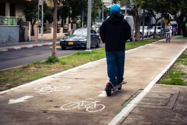 Tel Aviv, İsrail, 14 Ocak 2026 İnsanlar Rothschild Bulvarı boyunca elektrikli scooterlara biniyor. Tel Aviv 'in ağaçlarla kaplı merkezi caddesi, modern şehir yaşam tarzını yansıtıyor..