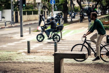 Tel Aviv, İsrail, 14 Ocak 2026. Bisikletçiler, Tel Aviv 'de Rothschild Bulvarı boyunca, modern şehir yaşam tarzını yansıtan, ağaçlarla çevrili, canlı bir merkez caddeye gidiyorlar..