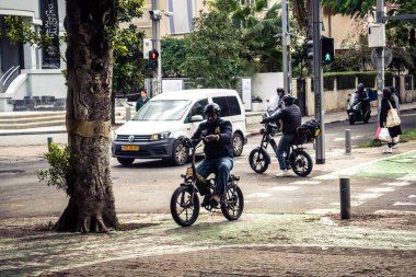 Tel Aviv, İsrail, 14 Ocak 2026. Bisikletçiler, Tel Aviv 'de Rothschild Bulvarı boyunca, modern şehir yaşam tarzını yansıtan, ağaçlarla çevrili, canlı bir merkez caddeye gidiyorlar..