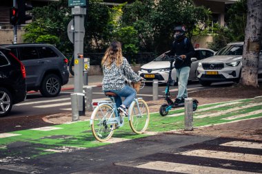 Tel Aviv, İsrail, 14 Ocak 2026. Bisikletçiler, Tel Aviv 'de Rothschild Bulvarı boyunca, modern şehir yaşam tarzını yansıtan, ağaçlarla çevrili, canlı bir merkez caddeye gidiyorlar..