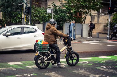 Tel Aviv, İsrail, 14 Ocak 2026. Bisikletçiler, Tel Aviv 'de Rothschild Bulvarı boyunca, modern şehir yaşam tarzını yansıtan, ağaçlarla çevrili, canlı bir merkez caddeye gidiyorlar..