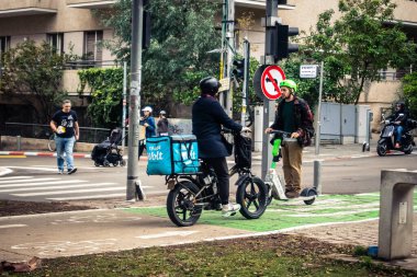 Tel Aviv, İsrail, 14 Ocak 2026. Bisikletçiler, Tel Aviv 'de Rothschild Bulvarı boyunca, modern şehir yaşam tarzını yansıtan, ağaçlarla çevrili, canlı bir merkez caddeye gidiyorlar..