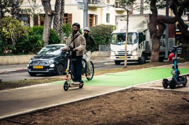 Tel Aviv, İsrail, 14 Ocak 2026 İnsanlar Rothschild Bulvarı boyunca elektrikli scooterlara biniyor. Tel Aviv 'in ağaçlarla kaplı merkezi caddesi, modern şehir yaşam tarzını yansıtıyor..