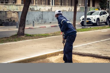 Tel Aviv, İsrail, 21 Ocak 2026 Tel Aviv Şehir Parkları Departmanı 'nın bir çalışanı Rothschild Bulvarı' na dekoratif çakıl yayıyor..