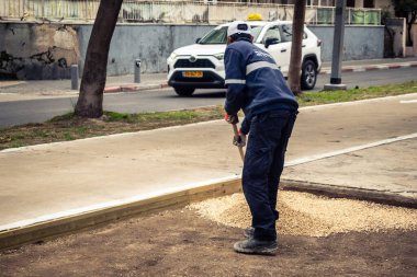 Tel Aviv, İsrail, 21 Ocak 2026 Tel Aviv Şehir Parkları Departmanı 'nın bir çalışanı Rothschild Bulvarı' na dekoratif çakıl yayıyor..