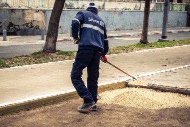 Tel Aviv, İsrail, 21 Ocak 2026 Tel Aviv Şehir Parkları Departmanı 'nın bir çalışanı Rothschild Bulvarı' na dekoratif çakıl yayıyor..