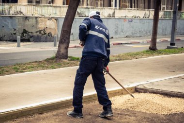Tel Aviv, İsrail, 21 Ocak 2026 Tel Aviv Şehir Parkları Departmanı 'nın bir çalışanı Rothschild Bulvarı' na dekoratif çakıl yayıyor..
