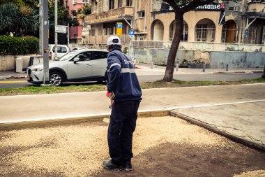 Tel Aviv, İsrail, 21 Ocak 2026 Tel Aviv Şehir Parkları Departmanı 'nın bir çalışanı Rothschild Bulvarı' na dekoratif çakıl yayıyor..
