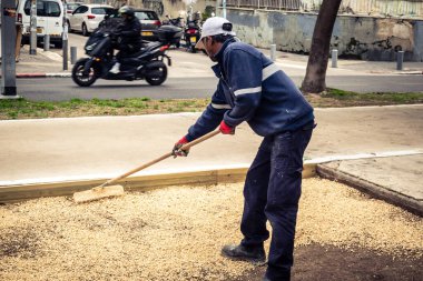 Tel Aviv, İsrail, 21 Ocak 2026 Tel Aviv Şehir Parkları Departmanı 'nın bir çalışanı Rothschild Bulvarı' na dekoratif çakıl yayıyor..