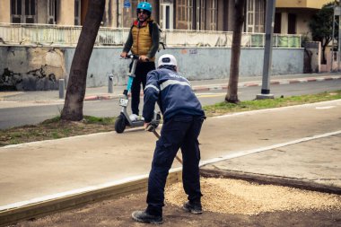 Tel Aviv, İsrail, 21 Ocak 2026 Tel Aviv Şehir Parkları Departmanı 'nın bir çalışanı Rothschild Bulvarı' na dekoratif çakıl yayıyor..