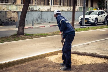 Tel Aviv, İsrail, 21 Ocak 2026 Tel Aviv Şehir Parkları Departmanı 'nın bir çalışanı Rothschild Bulvarı' na dekoratif çakıl yayıyor..