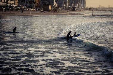 Tel Aviv, İsrail, 25 Ocak 2026 Tel Aviv plajında sörf yapan gençler. Bu plaj, Tel Aviv sakinleri için fiziksel aktivite ve rahatlama için vazgeçilmez bir sığınak olmaya devam ediyor..